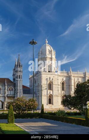 Vista su un parco e lo storico Mosteiro dos Jeronimos (Monastero di Jeronimos) a Belem, Lisbona, Portogallo, in una mattinata di sole. Foto Stock