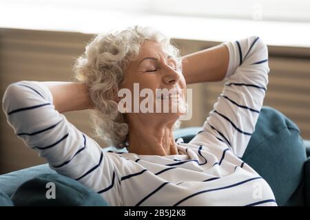 Felice anziana donna rilassarsi dormire su un comodo divano Foto Stock
