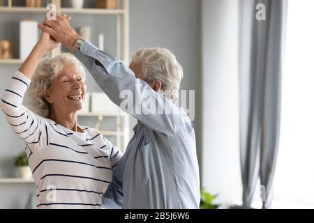 Il marito maturo e la moglie sono pieni di gioia e danzano nel soggiorno Foto Stock
