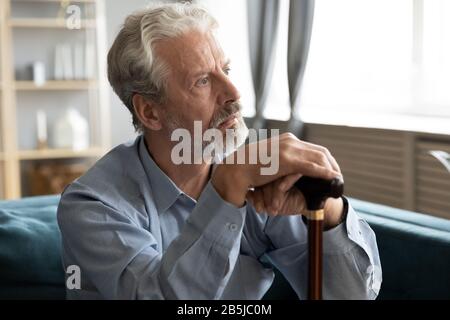 Vecchio infelice con lo sguardo della canna in lutto di distanza Foto Stock