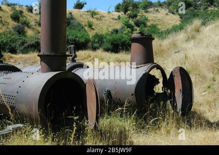 Caldaie della vecchia miniera Golden Progress ruggine accanto alla testa del fungo dove hanno alimentato il meccanismo di avvolgimento per l'albero della miniera. Foto Stock