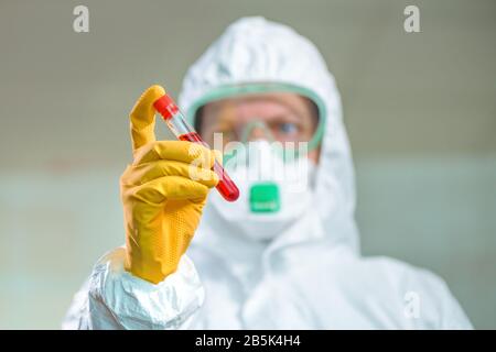 Epidemiologist che esamina la provetta di analisi del campione medico in quarantena virale, testando il sangue del paziente durante l'epidemia di infezione virale Foto Stock