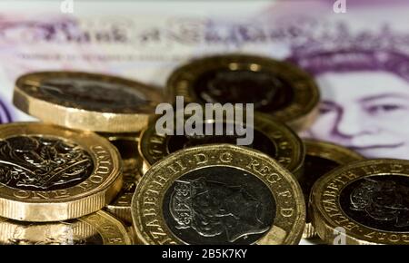 Monete inglesi da una libbra con la nuova banconota da venti libbre in polimero 2020 sullo sfondo Foto Stock
