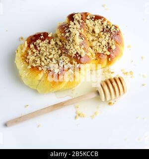 Concetto di cucina rumena. Mucenici fatti in casa, dolci tradizionali cosparsi di miele e noci tritate isolati su sfondo bianco. Foto Stock