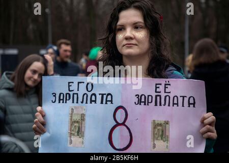 Mosca, Russia. 8th di marzo 2020 un partecipante a un rally "arco 8 - celebrare correttamente la festa" per la solidarietà delle donne e i diritti delle donne, Organizzato dal gruppo di attivisti femminili per celebrare la Giornata Internazionale della Donna a Mosca, il Sokolniki Hyde Park.The manifestanti si levano in piedi fuori per un progetto di legge che protegge le donne dalla violenza domestica, per l'uguaglianza, contro il sessismo, l'oggettivazione femminile, e la repressione politica. Un banner legge 'il suo stipendio (a sinistra), il suo stipendio (a destra)' Foto Stock