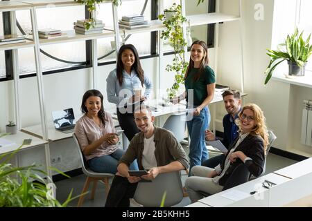 I colleghi più numerosi e felici discutono delle idee durante il briefing Foto Stock