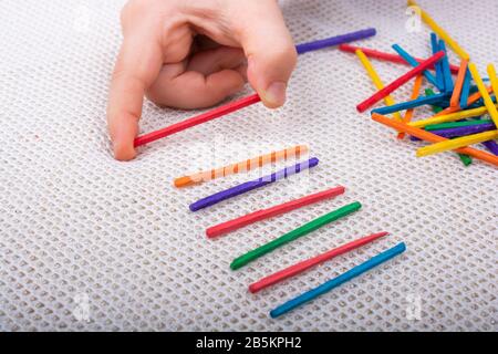 Kid a giocare con i colori dei bastoncini di legno per la creatività su sfondo bianco Foto Stock