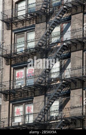 Black Metal fuoco fuga scale di condominio in Cina Town con cinese scrittura su finestre Foto Stock