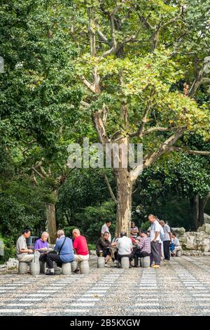 Uomini cinesi anziani che giocano a carte nell'area esterna dei posti a sedere in Concessione Francese Est, Shanghai Foto Stock