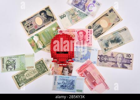 Gruppo ledo rosso banca piggy circondato da diverse valute carta note da tutto il mondo Foto Stock