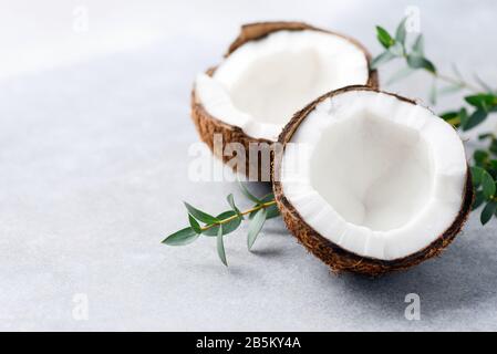 Noce di cocco dimezzato su sfondo di cemento con spazio di copia per elementi di testo o di design Foto Stock