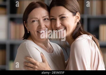 Felice donna matura che tocca le teste con bambino sorridente grugnup. Foto Stock