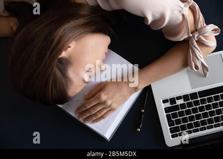Sopra la vista restless giovane donna freelancer dormire sul tavolo. Foto Stock