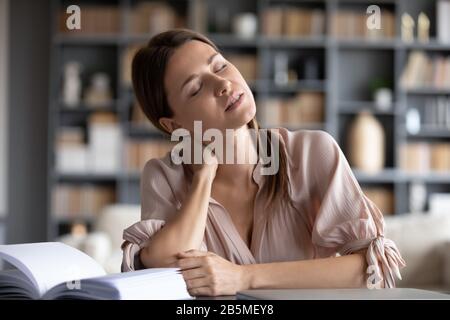 Giovane donna stressata che soffre di dolore al collo. Foto Stock