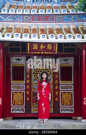 Una giovane donna vietnamita indossa un tradizionale abito Ao dai nelle strade della vecchia Hoi An Foto Stock