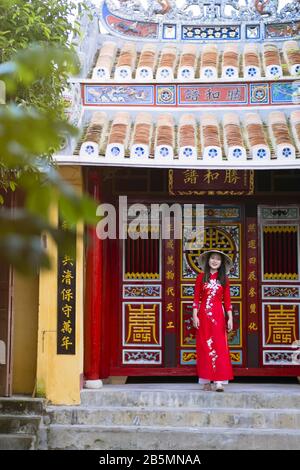 Una giovane donna vietnamita indossa un tradizionale abito Ao dai nelle strade della vecchia Hoi An Foto Stock