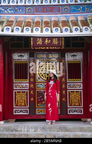 Una giovane donna vietnamita indossa un tradizionale abito Ao dai nelle strade della vecchia Hoi An Foto Stock