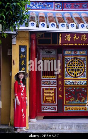 Una giovane donna vietnamita indossa un tradizionale abito Ao dai nelle strade della vecchia Hoi An Foto Stock