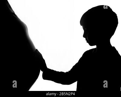 Silhouette di un ragazzo che tocca il ventre della madre incinta. Aspettandosi un fratello. Foto Stock