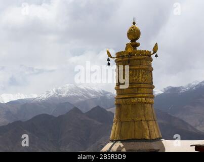 Bandiera della vittoria dorata con le montagne sullo sfondo, monastero di Drepung, Lhasa, Tibet Foto Stock