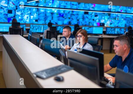 Gruppo di sicurezza agli operatori dei centri dati (amministratori) lavorando in un gruppo a un monitoraggio TVCC sala mentre guardando i monitor multipli ( computer sc Foto Stock