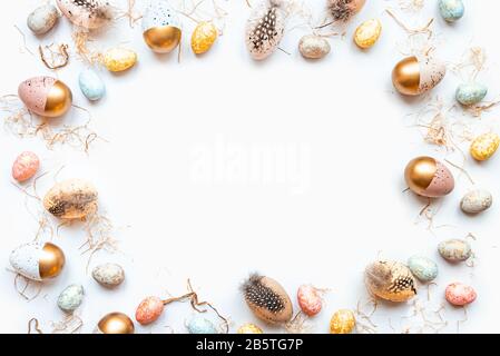 Vista dall'alto delle uova di Pasqua colorate con vernice dorata in diversi modelli. Sfondo bianco. Spazio di copia. Foto Stock