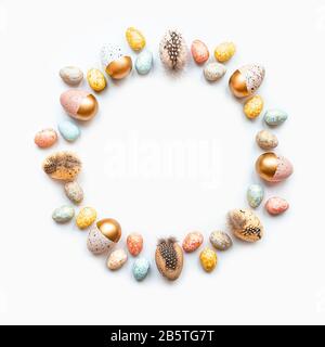 Vista dall'alto delle uova di Pasqua colorate con vernice dorata in diversi modelli disposti in cerchio. Sfondo bianco. Spazio di copia Foto Stock