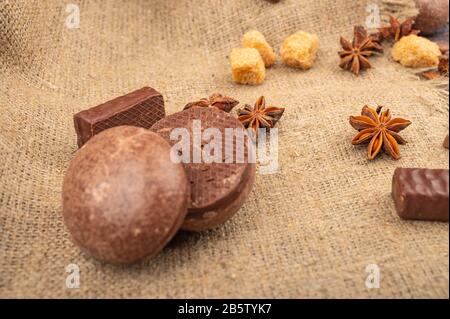 Torte di cioccolato, cioccolato, pezzi di zucchero di canna e anice stellato su uno sfondo di tessuto di homespun ruvido. Primo piano Foto Stock