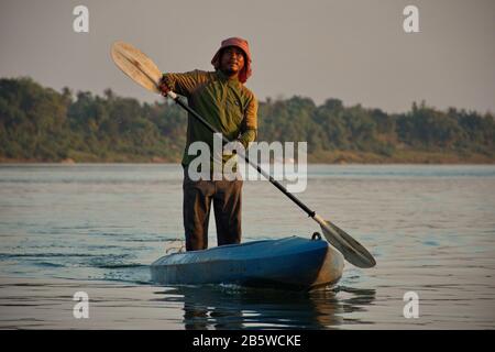 Uomo che pagaia in kayak durante il tramonto sul fiume Mekong Foto Stock