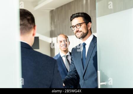 Gruppo di fiduciosi uomini d'affari salutano con una stretta di mano durante la riunione d'affari in ufficio moderno o chiudendo l'accordo di trattativa scuotendo le mani. Foto Stock