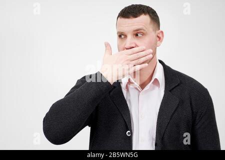 ritratto dell'uomo con la mano sulla bocca guardando da parte, stordita e senza parole concetto Foto Stock