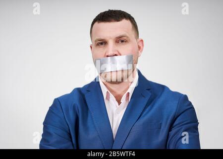 l'uomo ha un grande pezzo di nastro industriale nero che copre la sua bocca, concetto di silenzio Foto Stock