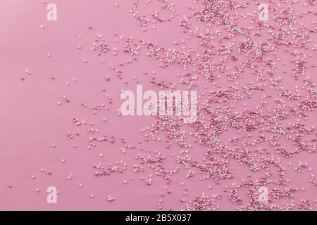 Cospargete lo sfondo con una farcitura rosa e bianca sparpagliata su sfondo rosa pallido con spazio per testo - vista dall'alto Foto Stock