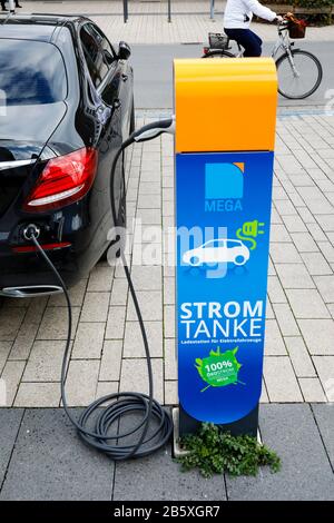Monheim am Rhein, Renania Settentrionale-Vestfalia, Germania - un'auto elettrica refuels eco-potenza in una stazione di rifornimento elettrico su un parcheggio pubblico. Monheim Foto Stock