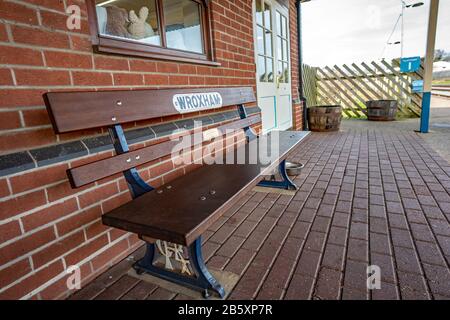 26 Wroxham, Norfolk, Regno Unito – 07 Marzo 2020. Primo piano di posti a sedere su panchina di legno sulla stazione ferroviaria di vapore di Bure Valley nel villaggio di Hoveton e Wroxh Foto Stock