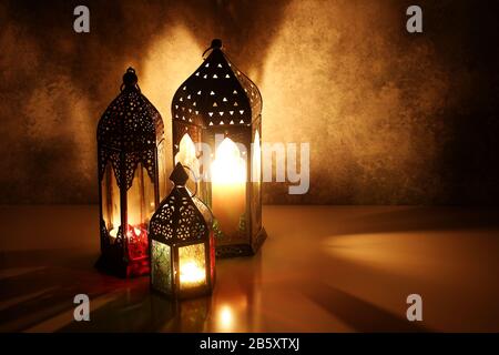 Lanterne arabe ornamentali con candele accese sul tavolo che si illuminano di notte. Biglietto di auguri festivo, invito per il mese santo musulmano Ramadan Kareem Foto Stock