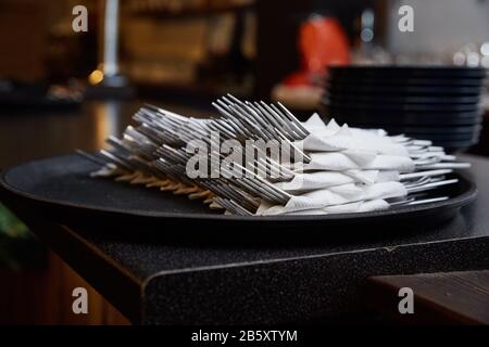 forchette avvolte in un tovagliolo su un vassoio in una caffetteria scura Foto Stock