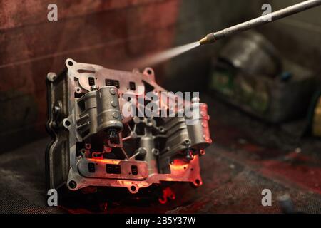 Usare la pistola per sabbiatura per pulire la parte sporca del motore dell'automobile, la ripresa di primo piano orizzontale, lo spazio di copia Foto Stock