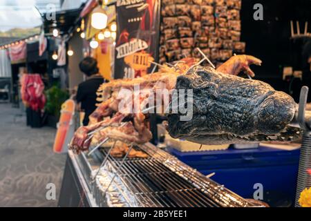 Il coccodrillo arrosto è alla griglia, mentre il tradizionale cibo di strada tailandese asiatico. Foto Stock