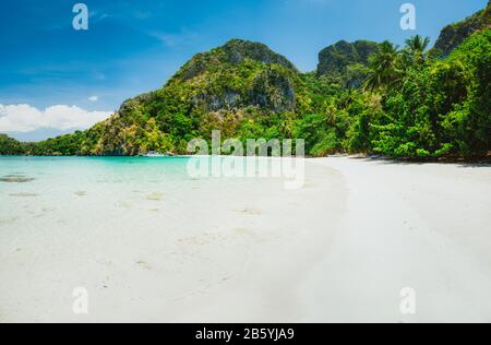 Una splendida spiaggia di sabbia tropicale con colline calcaree e lussureggianti alberi verdi della giungla. Concetto di vacanza di festa. Foto Stock
