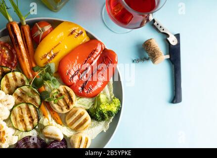 Verdure grigliate biologiche peperone, cavolfiore, broccoli, carote, funghi e cipolle rosse servite su un piatto rotondo. Cena vegetariana con servizio di Ro Foto Stock