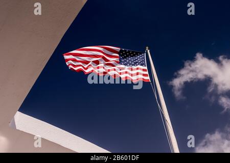 Bandiera americana che soffia nel vento sopra l'USS Arizona Memorial a Pearl Harbour, Hawaii Foto Stock