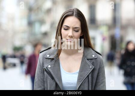 Vista frontale ritratto di una giovane donna depressa a piedi sulla strada della città Foto Stock