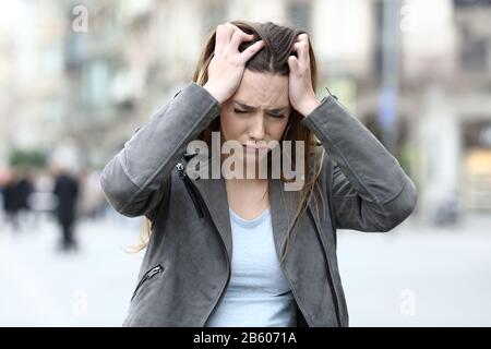 Ragazza stressata afferrare la testa lamentarsi da sola sulla strada della città Foto Stock