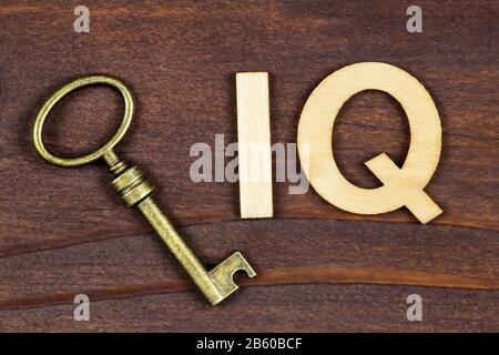 Quoziente di intelligenza, prova di iq, concetto del cervello, chiave con le lettere su uno sfondo marrone di legno Foto Stock