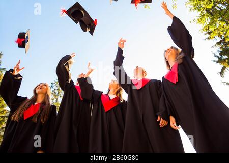 Cinque studenti di successo con le congratulazioni insieme gettando cappelli di laurea in aria e celebrare Foto Stock