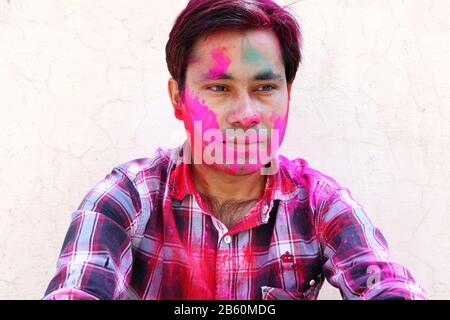 Closeup shot indiana di giovane uomo coperto con multi colore vernice secca a Holi festival. Foto Stock