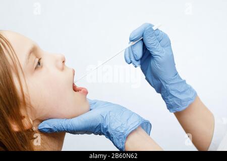 Pediatra o medico che prende il campione di test di saliva fom labbra della ragazza di età elementare che esegue Il test Di Saliva (Salivaomics) procedura diagnostica Foto Stock