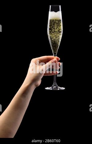 Donna mano che tiene un bicchiere di champagne frizzante isolato su nero. Foto Stock