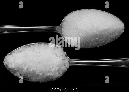 Cucchiaio con sale e zucchero. Su sfondo nero. Foto Stock